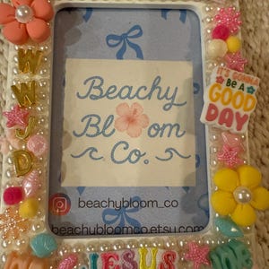 May include: A white rectangular photo frame adorned with pearls, vibrant flowers, and the phrases "LOVE LIKE" and "JESUS". The frame displays the text "Beachy Bloom Co." and "It's Gonna Be A GOOD DAY".