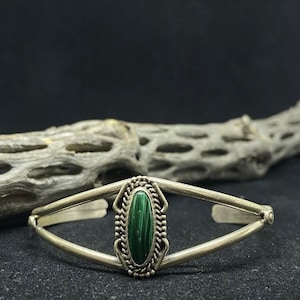 May include: A silver bracelet with a green malachite stone set in a decorative silver bezel.