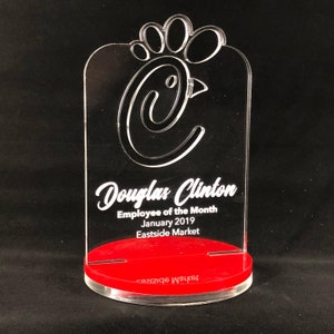 May include: A clear acrylic award with a red base. The award features a stylized chicken silhouette and the text "Douglas Clinton Employee of the Month January 2019 Eastside Market".