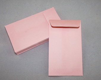 May include: A stack of pink envelopes, with one envelope on top of the stack. The envelope on top is open and ready to be used.