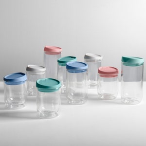 May include: A set of nine glass cups with lids in various colours, including blue, green, and pink. The cups are clear glass and have a double-walled design.