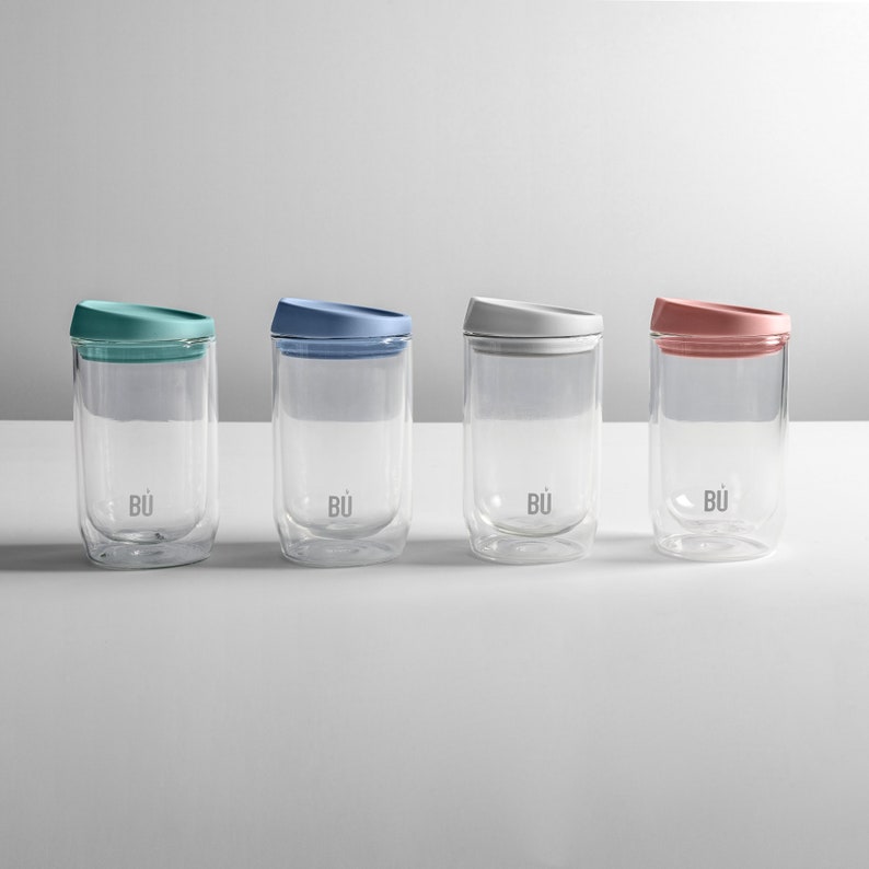 May include: Four double-walled glass mugs with lids in different colours: teal, blue, white, and pink. Each mug has the word "B&Uuml;" printed on the bottom.