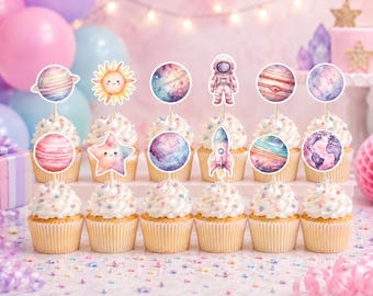 May include: A collection of cupcakes with white frosting and colorful sprinkles. Each cupcake is topped with a decorative space-themed pick, including planets, stars, a rocket, and an astronaut. Pink and blue balloons are in the background.