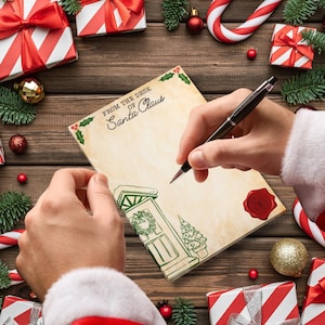 May include: A person writing on a letter from the desk of Santa Claus. The letter is decorated with a drawing of a door and a Christmas tree. The scene is surrounded by wrapped gifts, candy canes, and ornaments on a wooden surface.