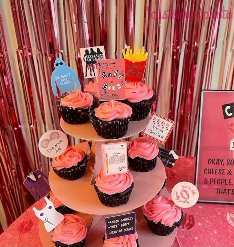 K&ouml;nnte beinhalten: Ein mehrst&ouml;ckiger Cupcake-St&auml;nder mit rosa glasierten Cupcakes und dekorativen Toppings. Zu den Toppings geh&ouml;ren eine blaue Figur, ein rosa Buch, ein Pommes-Frites-Beh&auml;lter und Text mit der Aufschrift "You go Glen Coco!" und "I'm a mouse, duh!"