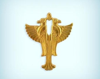 Puede incluir: Un colgante de metal dorado con un diseño estilizado de dos pájaros que se miran con las alas extendidas.