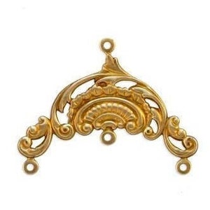 May include: Gold-toned metal pendant with a decorative, ornate design. The pendant has three loops for attaching to a chain or cord.