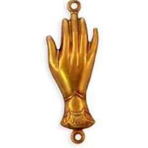 May include: A gold-toned metal hand charm with two loops for attaching to a necklace or bracelet. The hand is raised with fingers extended and the palm facing forward.