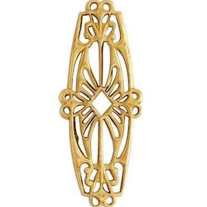 May include: Gold metal decorative embellishment with an intricate, ornate design. The embellishment is shaped like an oval with a diamond-shaped center.