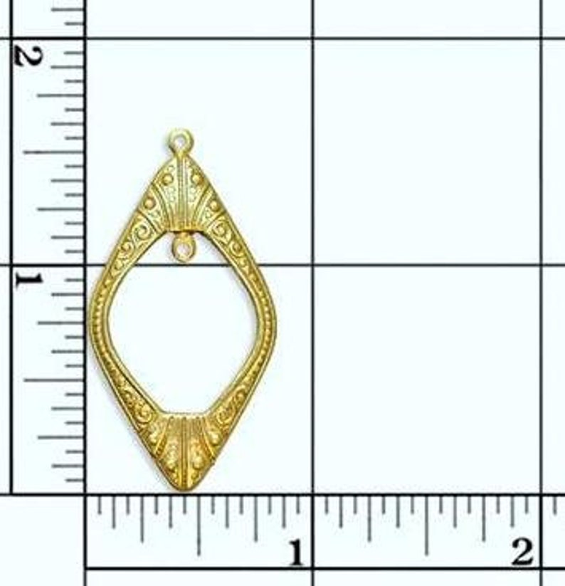 May include: Gold-toned metal pendant with a diamond-shaped frame and intricate details. The pendant measures approximately 1 inch in height.