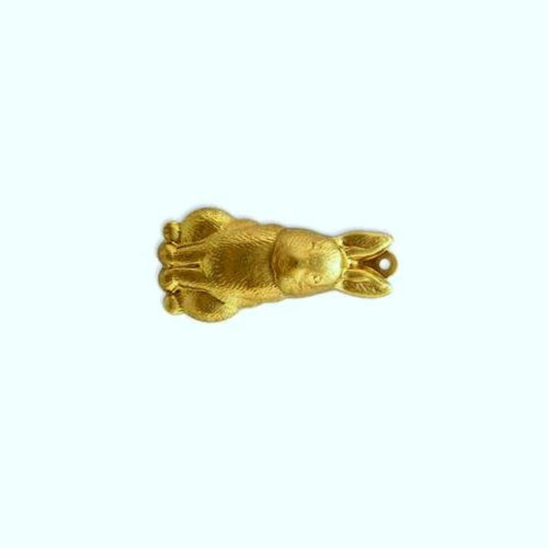 May include: A gold-colored rabbit charm with a detailed design. The charm is made of metal and has a loop for attaching to a necklace or bracelet.