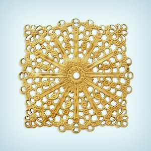 May include: A gold metal decorative piece with a circular design and intricate cutouts. The piece has a delicate, lacy appearance and is perfect for adding a touch of elegance to any project.