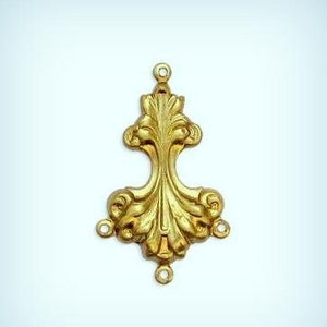 May include: Gold-toned metal decorative embellishment with a floral design. The embellishment has three loops on the top and three loops on the bottom.