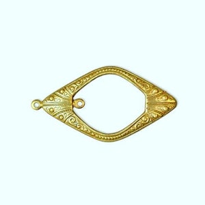 May include: A gold-toned metal frame with an ornate design. The frame has a diamond shape with a rounded opening in the center. The frame has two small loops on the top and bottom for attaching to a larger piece.