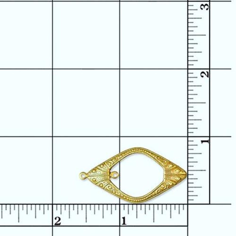 May include: Gold-toned metal frame with an ornate design. The frame is shaped like a teardrop and has a small loop at the top.