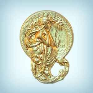 May include: A gold-toned metal plaque with a raised design of a woman in a flowing robe. The woman is holding a flower and is surrounded by leaves. The plaque is circular and has a decorative border.