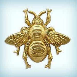May include: A gold-coloured metal bee figurine with detailed wings and legs. The bee is in a flying position with its wings spread out.