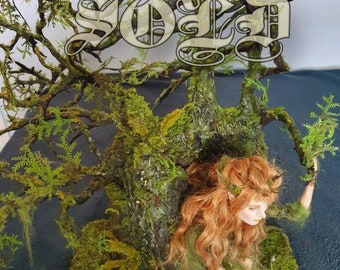 May include: A miniature fairy figurine with long red hair is nestled in a moss-covered tree trunk. The tree is decorated with moss and small mushrooms. The base of the tree is surrounded by moss and small mushrooms. The words "SOLD" are written in a decorative font above the tree. The words "Botanic Tales" are written in a decorative font below the tree.
