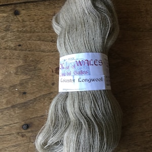 May include: A skein of light gray wool yarn labeled "Wool out of Wales, Lana dal Galles, Leicester Longwool".