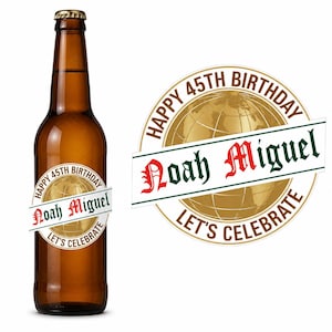 May include: A brown glass beer bottle with a circular label featuring a gold globe graphic, the text "HAPPY 45TH BIRTHDAY", "LET'S CELEBRATE", and the name "Noah Miguel" in a decorative font across a white banner overlaying the globe design.