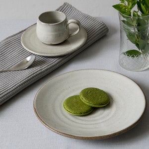 Puede incluir: Dos galletas de matcha verdes en un plato de cer&aacute;mica blanco sobre un fondo blanco. El plato tiene un dise&ntilde;o de espiral.