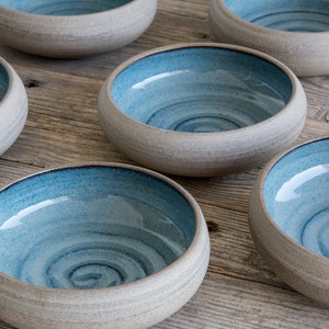 May include: Six ceramic bowls with a light gray exterior and a blue interior. The bowls have a swirl pattern on the inside.