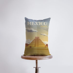 Könnte beinhalten: Ein braunes und beigefarbenes Kissen mit einem grafischen Design einer Pyramide vor einem Sonnenuntergangshimmel. Der Text "MEXICO" und "CHICHEN ITZA" ist auf dem Kissen aufgedruckt.