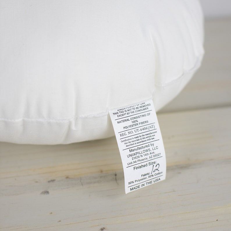 May include: A white pillow with a tag attached. The tag reads "THIS TAG IS NOT TO BE REMOVED EXCEPT BY THE CONSUMER" and lists the materials as 100% polyester fibres. The finished size is 30.48 cm.