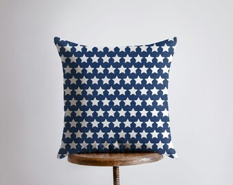 Op de afbeelding: Een blauw kussen met een wit sterrenpatroon. Het kussen ligt op een houten kruk.
