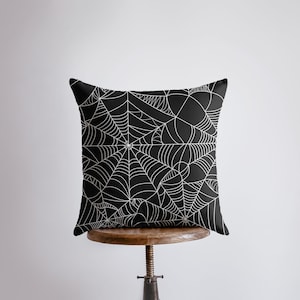 May include: Black throw pillow with a white spiderweb design.