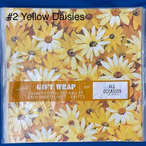 May include: Gift wrap featuring a pattern of yellow daisies on a brown background. The text on the package reads "Gift Wrap 50c 2 sheets total of 7.9 sq. ft. Each sheet (1.64 ft. x 2.41 ft.) All Occasion LW 3470 U"