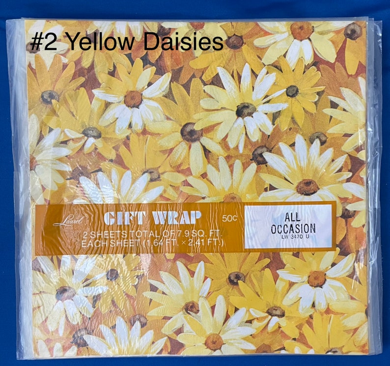 May include: Gift wrap featuring a pattern of yellow daisies on a brown background. The text on the package reads "Gift Wrap 50c 2 sheets total of 7.9 sq. ft. Each sheet (1.64 ft. x 2.41 ft.) All Occasion LW 3470 U"