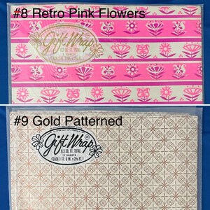 May include: Two rolls of gift wrap, one with a pink and white floral pattern and the other with a gold geometric pattern. Both rolls are labeled "Gift Wrap" and include the text "8.3 sq. ft. total, 2 sheets".