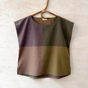 Può includere: Un top senza maniche caratterizzato da un design a blocchi di colore con quattro quadranti distinti in tonalità di viola spento, verde oliva e marrone. Il capo presenta uno scollo rotondo, un orlo dritto con spacchi laterali ed è su una gruccia.