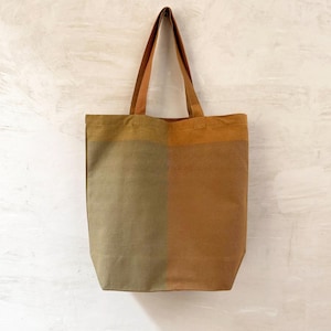 K&ouml;nnte beinhalten: Eine zweifarbige Tragetasche in Rost- und Olivgr&uuml;n. Die Tasche hat eine rechteckige Form mit flachem Boden und zwei langen Henkeln. Der Text "RUST / OLIVE" ist unten im Bild aufgedruckt.