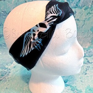 May include: Black headband with a blue and white graphic of wings. The headband is tied in a knot on top of the head.