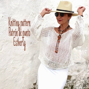 Pu&ograve; includere: Top bianco in crochet con una vestibilit&agrave; ampia e maniche lunghe. Il top &egrave; indossato da una persona con un cappello bianco e una lunga collana con perline marroni.