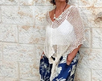 Puede incluir: Una mujer con un top blanco de ganchillo y pantalones de estampado floral azul. Está de pie frente a una pared de ladrillo blanco y lleva gafas de sol.