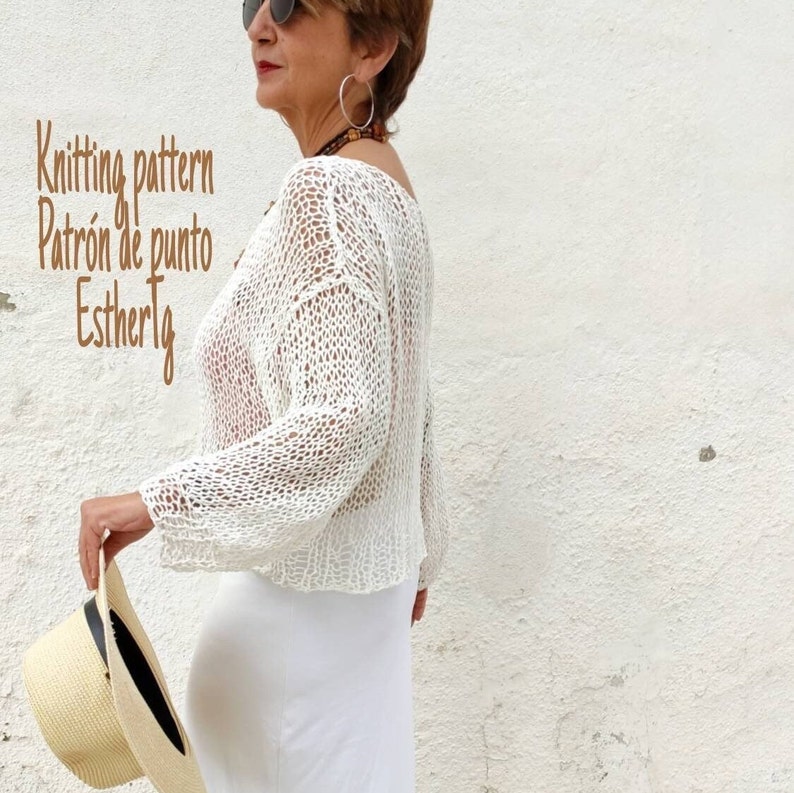 Pu&ograve; includere: Top bianco all'uncinetto con vestibilit&agrave; ampia e maniche lunghe. Il top presenta un delicato motivo traforato. Il testo "Knitting pattern Patr&oacute;n de punto Estherlg" &egrave; visibile nell'immagine.