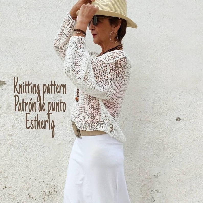 Pu&ograve; includere: Un top bianco all'uncinetto con una vestibilit&agrave; ampia e una scollatura ampia. Il top &egrave; realizzato con un delicato motivo a punto aperto. La modella indossa una gonna bianca e un cappello di paglia.