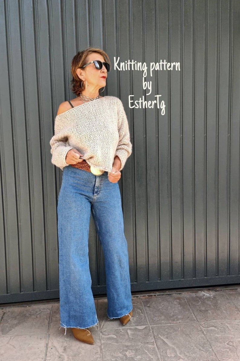 May include: A woman wearing a beige knitted sweater with a wide-leg, blue denim jean and brown heeled boots. The text "Knitting pattern by EstherTg" is displayed on a gray background.