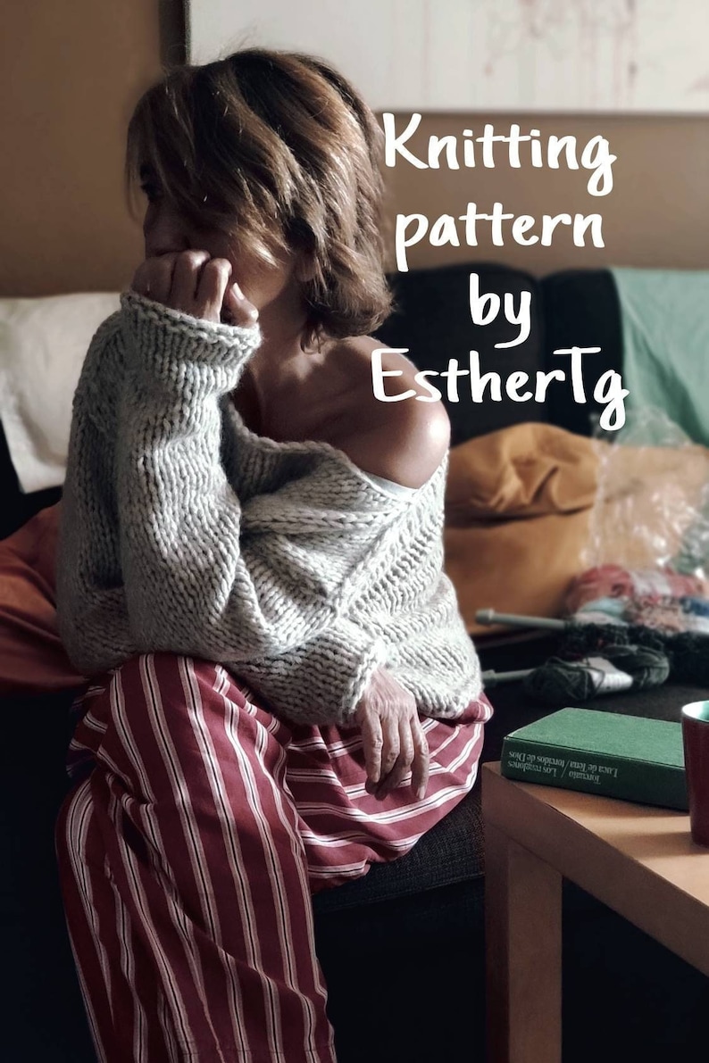 May include: A woman wearing a gray knitted sweater with a red and white striped shirt underneath. The sweater is off one shoulder and the woman is sitting on a couch. The text "Knitting pattern by EstherTg" is superimposed on the image.