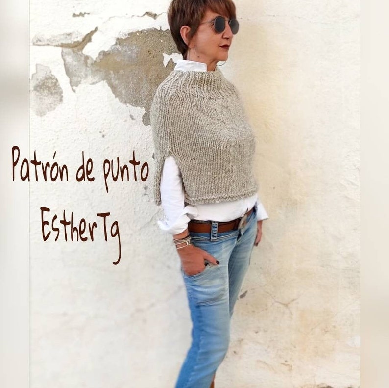 May include: A woman wearing a light brown knitted poncho with a white shirt and blue jeans. The text "Patr&oacute;n de punto EstherTg" is visible in the image.