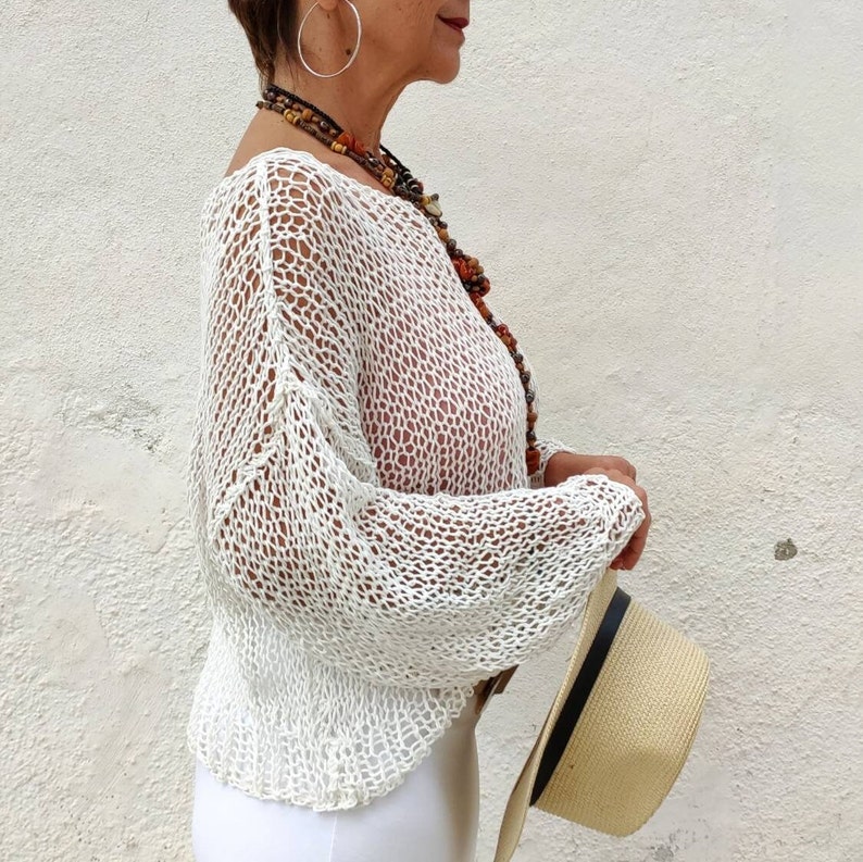 Pu&ograve; includere: Top bianco in crochet con una vestibilit&agrave; ampia e fluida e maniche lunghe. Il top &egrave; realizzato in un tessuto delicato e a trama aperta.
