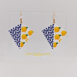 May include: A pair of beaded earrings with a geometric design. The earrings are diamond-shaped, featuring a pattern of yellow lemons on a white background, and a blue and white geometric pattern. The earrings have gold-colored hooks.