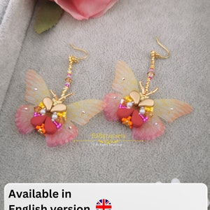 May include: A pair of gold butterfly earrings with pink and yellow wings, red and orange beads, and a gold chain. The earrings are available in English, French, and Italian.