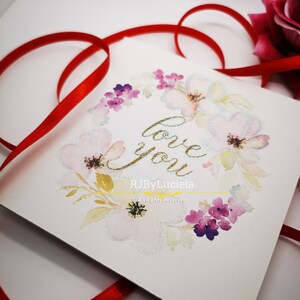 May include: A white card with a watercolor floral wreath and the words "love you" in gold glitter lettering. The card is signed "RJByLuciela" and includes the copyright notice "&copy;All Rights Reserved".