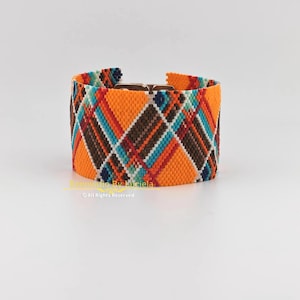 May include: Wide, orange beaded bracelet with a geometric pattern in brown, teal, and red. The bracelet has a metal clasp and is displayed on a white background. The text "Renovatio By Luciela" and "All Rights Reserved" are visible.
