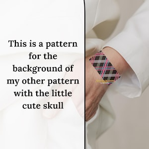 May include: A black, pink, and white woven bracelet with a plaid pattern. The bracelet is on a person's wrist.