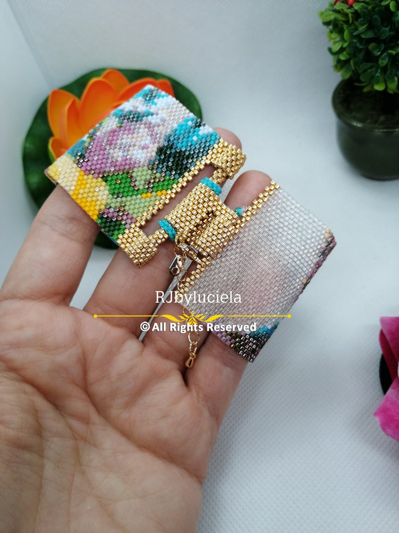 May include: A pair of colorful beaded earrings with a gold-tone metal clasp. The earrings are made with small beads in a variety of colors, including pink, blue, green, and yellow. The earrings are hanging from a gold-tone metal chain.